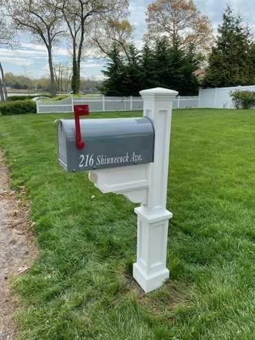 A mailbox in a grassy area with a sign on it.
