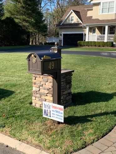 A mailbox in front of a house with a sign on it.