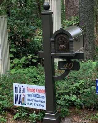 Two mailboxes in front of a wooded area.