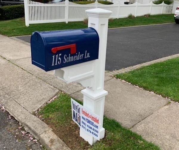 A mailbox with a sign on it in front of a house.