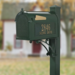 A green mailbox in front of a house.