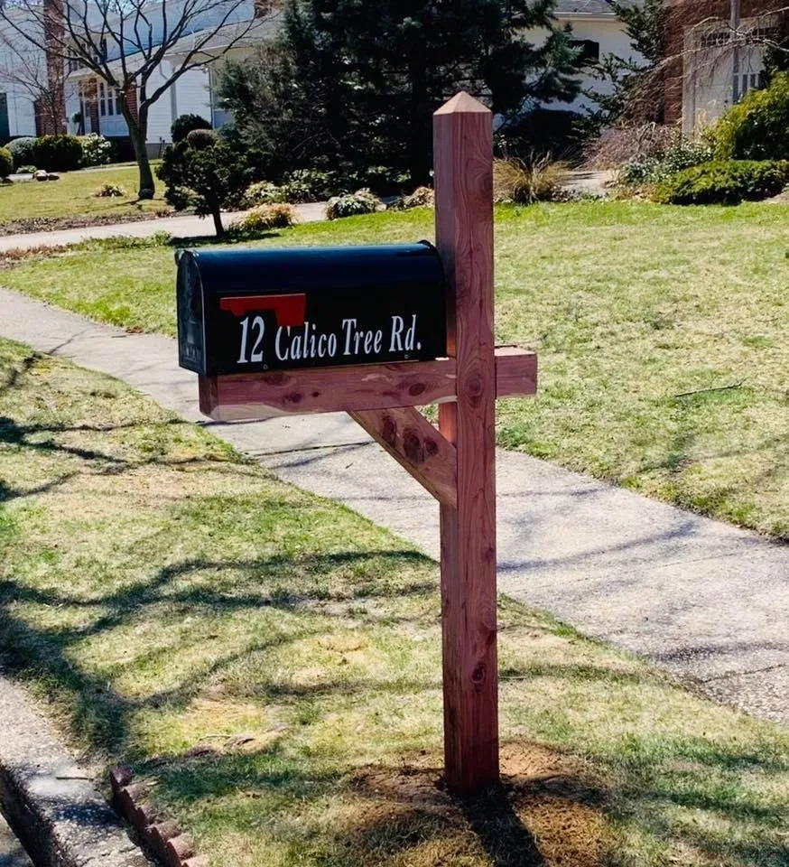 A Cedar Deluxe With Janzer Mailbox & Installation with a sign on it in front of a house.